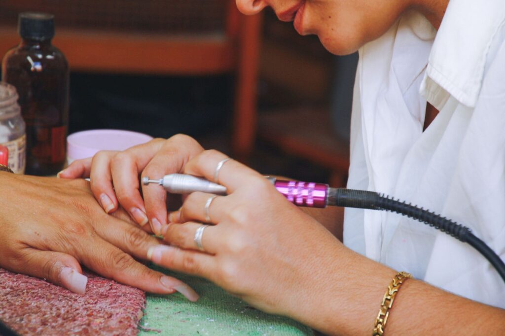 Nail technician filing and shaping nails during a manicure service